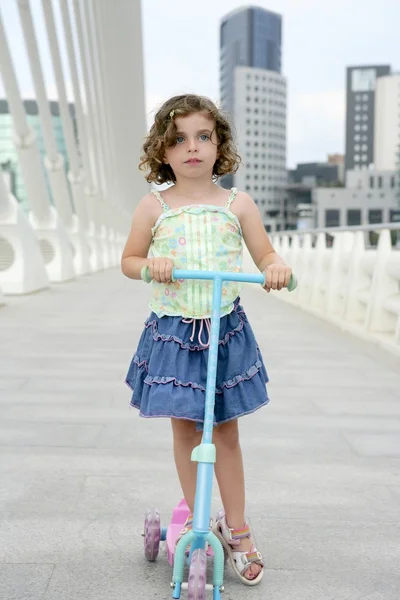 滑板车在城市的黑发小女孩 — 图库照片