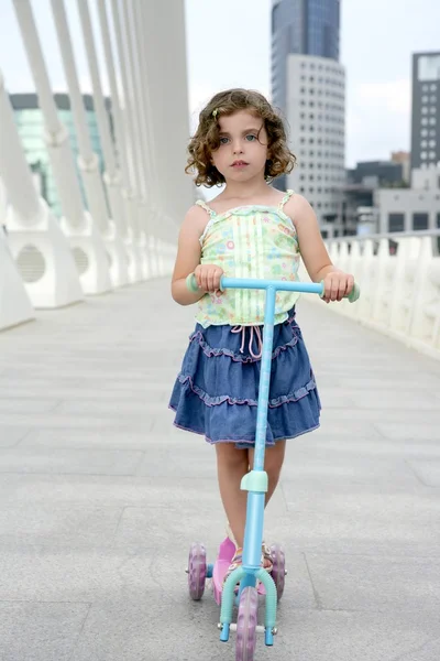 滑板车在城市的黑发小女孩 — 图库照片