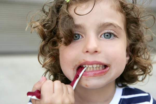 Kleines Mädchen isst süße Bonbons mit schmutzigem Gesicht — Stockfoto