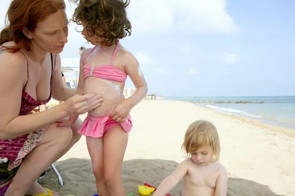 Figlia e madre sulla spiaggia crema solare umidità — Foto Stock