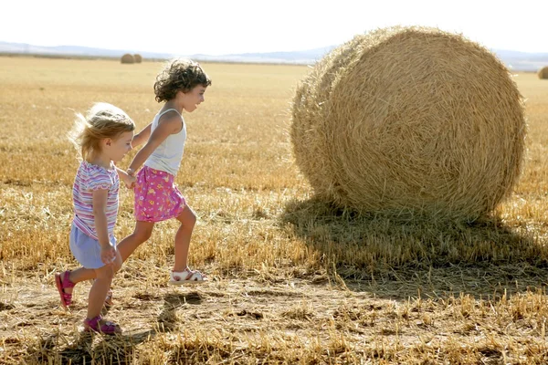 Chicas jugando con el trigo redondo pacas secas — Foto de Stock