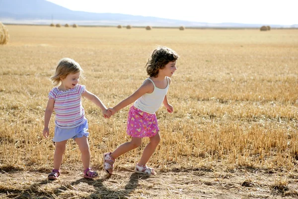 Meninas brincando com os fardos secos de trigo redondo — Fotografia de Stock