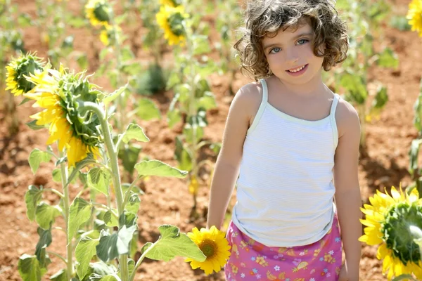 Vacker liten flicka i ett sommaren solros fält — Stockfoto