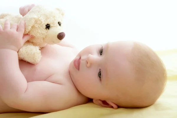 Baby playing teddy bear laying on bed — Stock Photo, Image