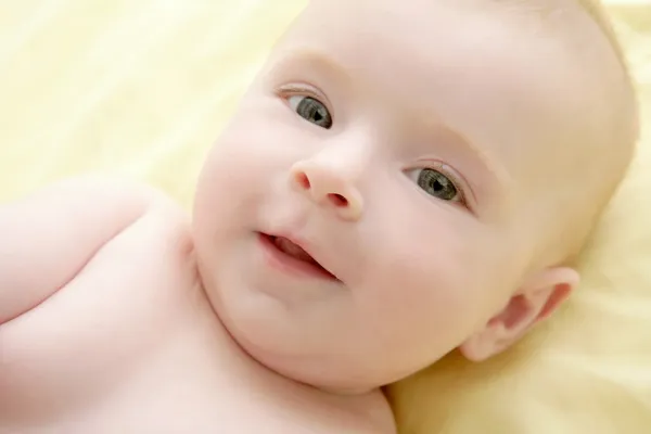 Blonda lilla bebis på sängen stående — Stockfoto