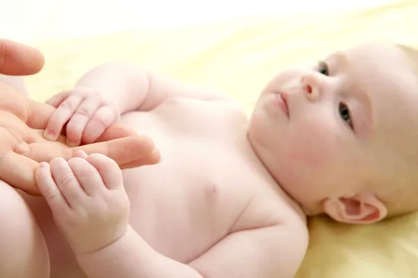 Nude blond baby playing mother hands — Stock Photo, Image