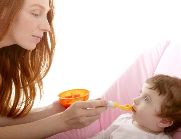 Мать кормит ребенка желтой ложкой — стоковое фото