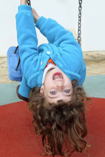 Kleines Mädchen kopfüber auf Parkspielplatz-Schaukel — Stockfoto