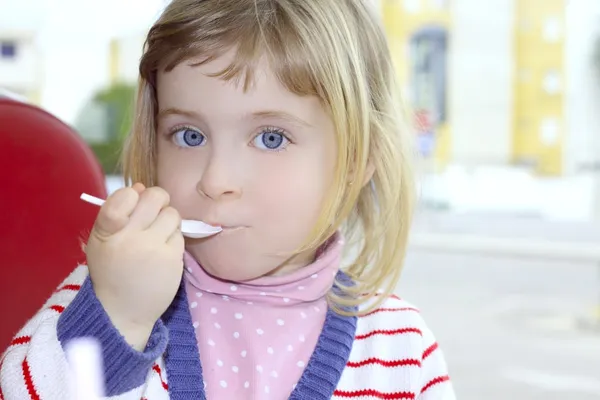 スプーンで食べるブロンド小さな少女の肖像画 — ストック写真