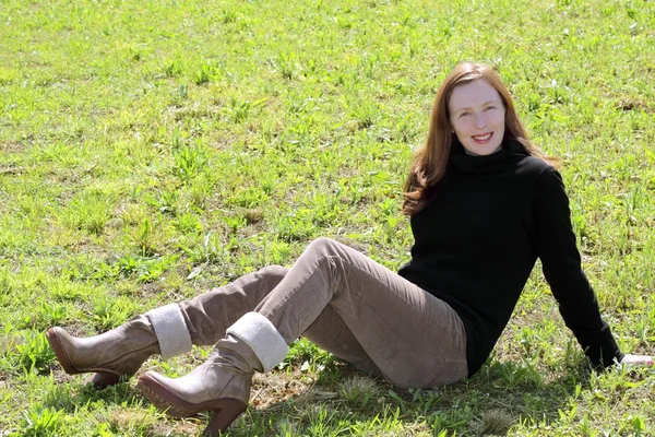 红头发的女人坐在草地上的草灯芯绒裤子 — 图库照片
