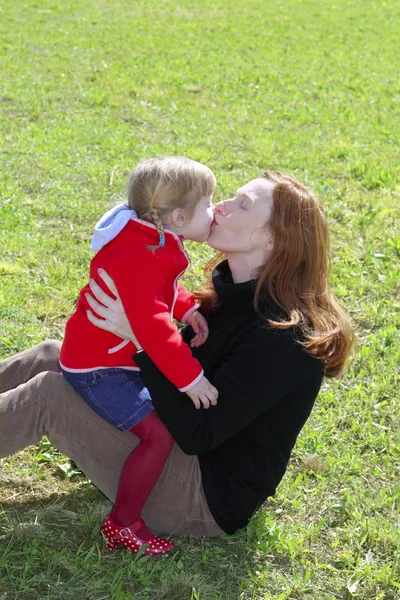 Мать и дочь целуют губы на лугу — стоковое фото