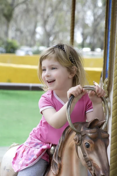 Pequena menina loira jogando cavalos alegre ir ao redor — Fotografia de Stock