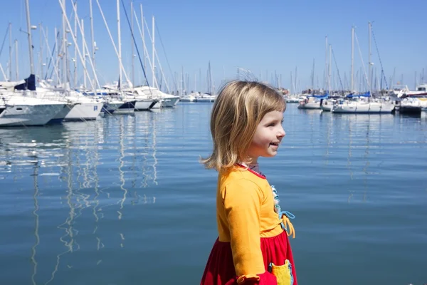 Bionda bambina passeggiando nel porto turistico blu — Foto Stock