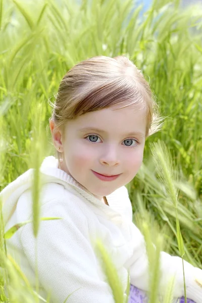 Yeşil sivri çayır üzerinde oturup mutlu sarışın kız — Stok fotoğraf