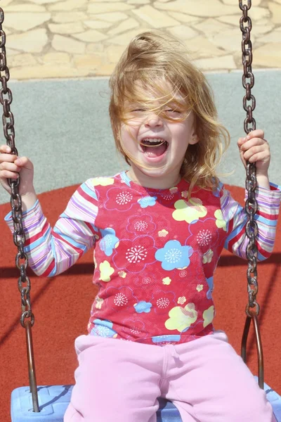 Niña rubia balanceándose en el parque swing cabello desordenado —  Fotos de Stock