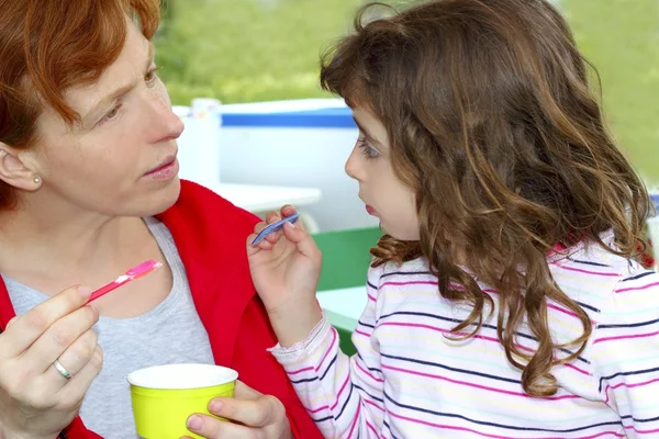 Мать и дочь едят мороженое разговаривая — стоковое фото