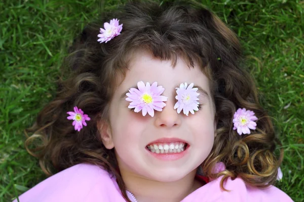 Маленькая девочка возлагает траву ромашка цветы в глаза — стоковое фото