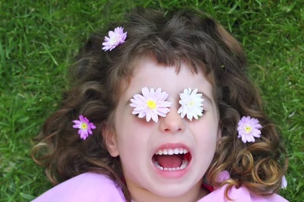 Liten flicka om gräs daisiy blommor i ögonen — Stockfoto