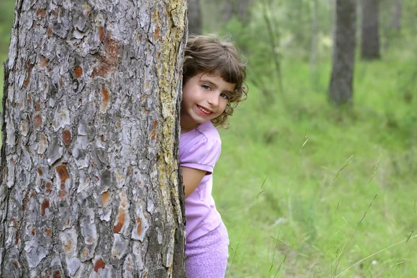 小さな女の子隠す公園木トランク緑の屋外 — ストック写真