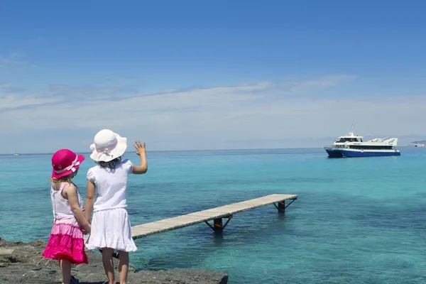 Dvě dívky turistické tyrkysové moře sbohem rukou gesto — Stock fotografie