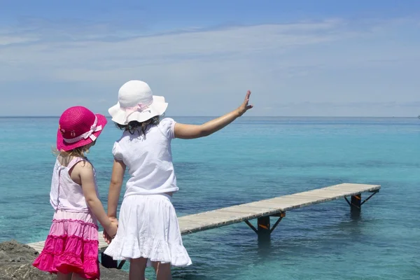 Zwei Mädchen türkisfarbenes Meer zum Abschied Handgeste — Stockfoto