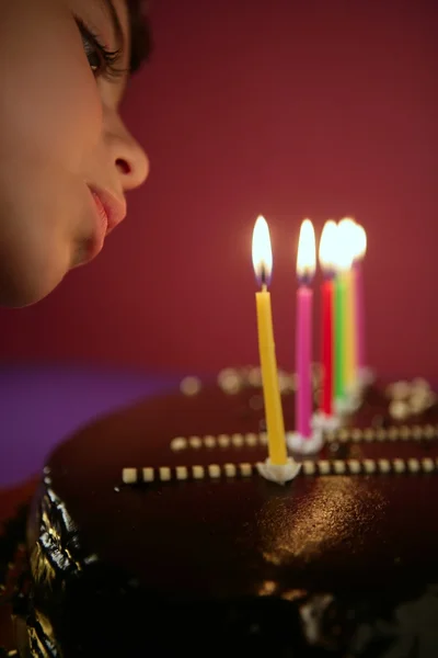 少女がチョコレートの誕生日ケーキのろうそくを吹き — ストック写真
