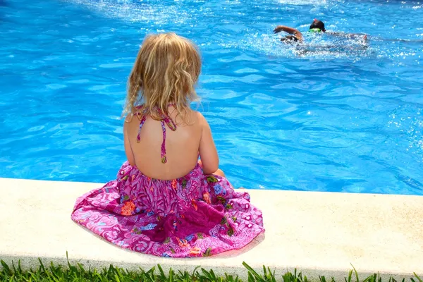 Little blond girl sitting rear back swimming pool — Stock Photo, Image