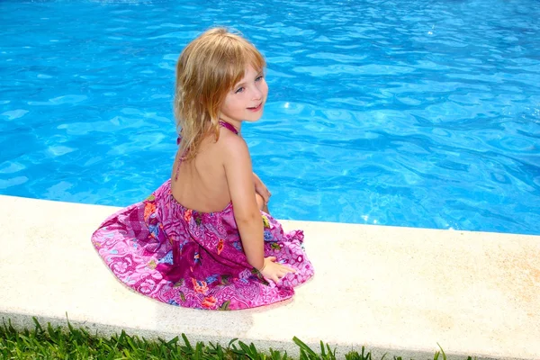 Liten blond flicka sitter leende swimmingpool — Stockfoto