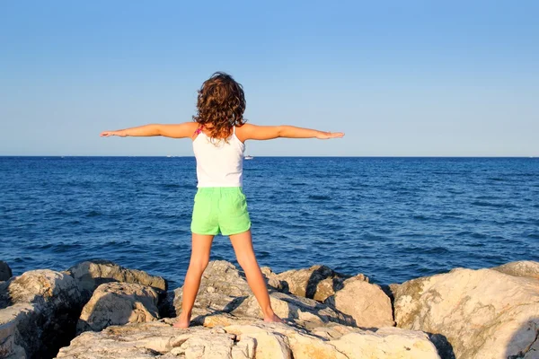 Девушка с распростертыми объятиями, глядя на синий океан моря, чувствует свободу — стоковое фото