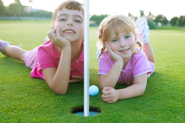 Golf hermanas niñas relajado por la colocación de bola agujero verde —  Fotos de Stock