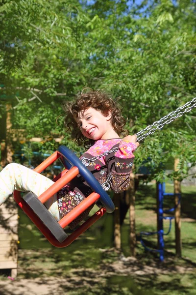 Chica balanceándose en swing feliz en los árboles al aire libre — Foto de Stock