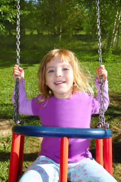 Dívka houpání na houpačce šťastný v luční trávy park — Stock fotografie