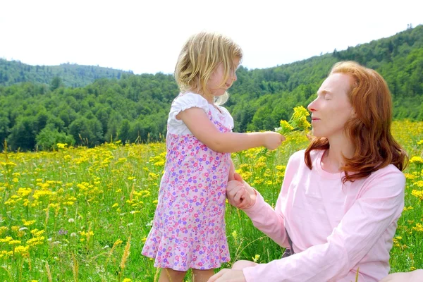 Dotter och mor spelar i blommor äng — Stockfoto
