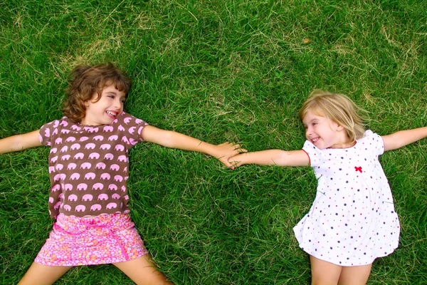 两个妹妹躺在蓝绿色草地上的女孩 — 图库照片