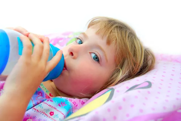 Dívka pití láhev mléka na posteli — Stock fotografie