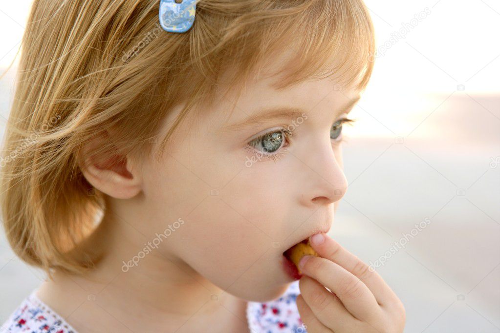 Blond little girl closeup portrait eating biscuit