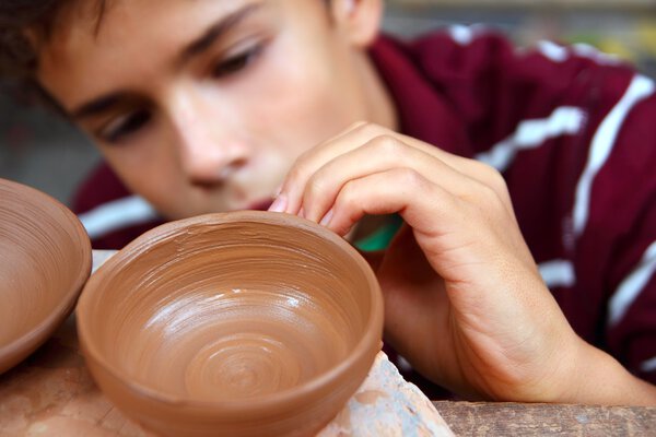 Boy teen potter clay bowl working in pottery workshop