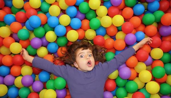 Renkli topları eğlence parkı el yalan küçük kız — Stok fotoğraf