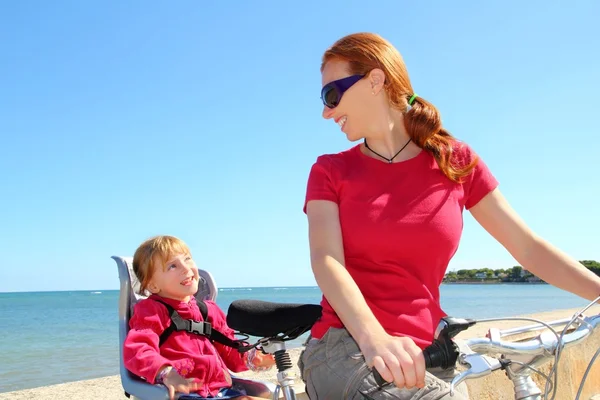 Dotter och mor på cykel i stranden havet — Stockfoto