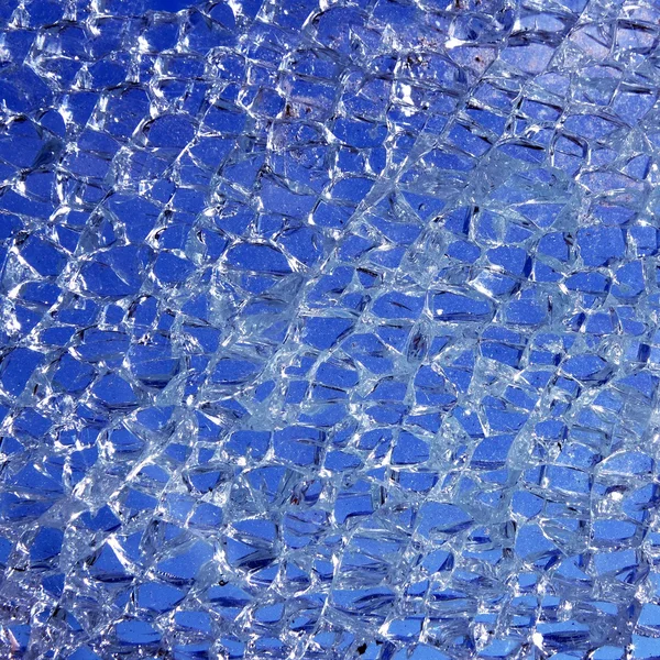 Vidro quebrado rachado sobre fundo azul — Fotografia de Stock