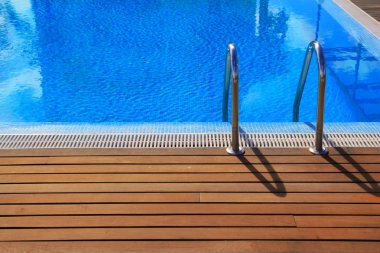 Blue swimming pool with teak wood flooring clipart