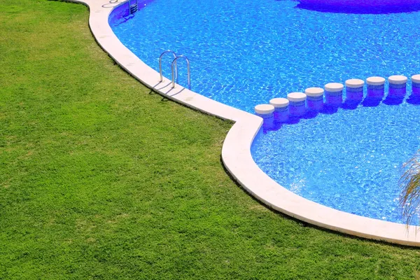 Блакитна плитка басейн з зеленим трав'яним садом — стокове фото