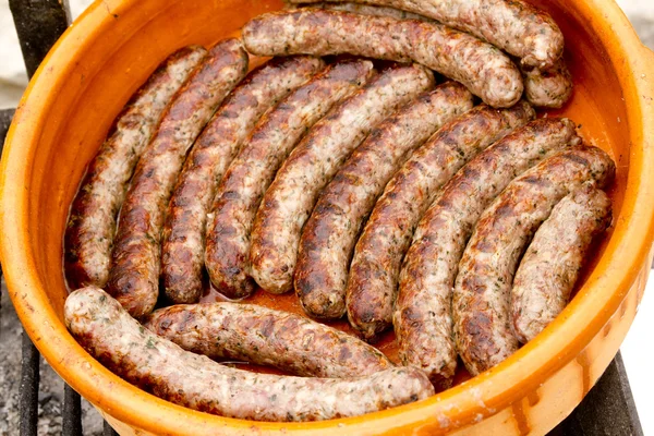Varkensvlees worst in een rij klei braadpan — Stockfoto