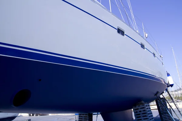 Парусная лодка синего цвета, выброшенная на берег для покраски — стоковое фото