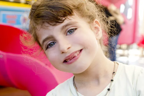 Bruna ragazza dentellata sorridente nel parco giochi rosso — Foto Stock