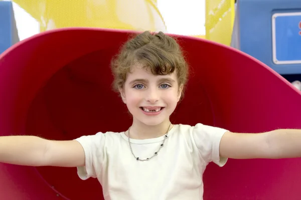 Brunetka dziewczynka wcięciami uśmiechający się w czerwony plac zabaw dla dzieci — Zdjęcie stockowe