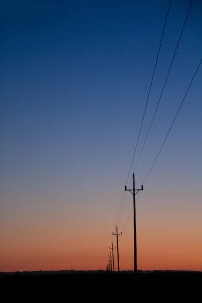 Electric power lines in sunset blue red orange — Stock Photo, Image
