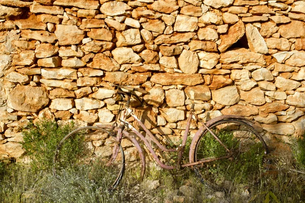 Bicicletta invecchiata arrugginita su muro di pietra romantica malinconia — Foto Stock