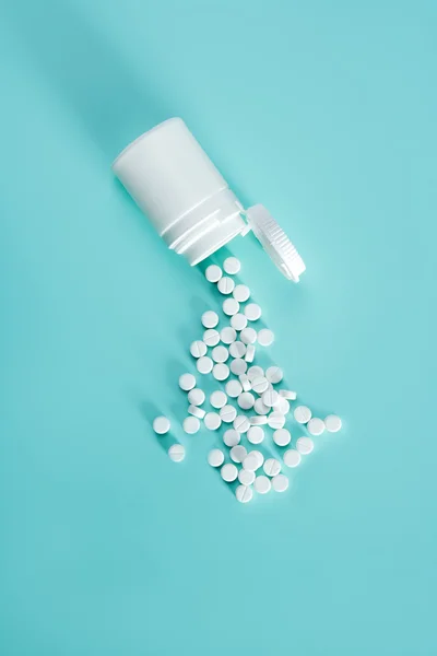 Fles met witte pillen komen uit op groene achtergrond — Stockfoto