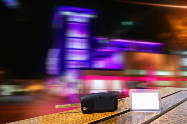 Autoverhuur toetsen op houten tafel in nacht stadslichten — Stockfoto